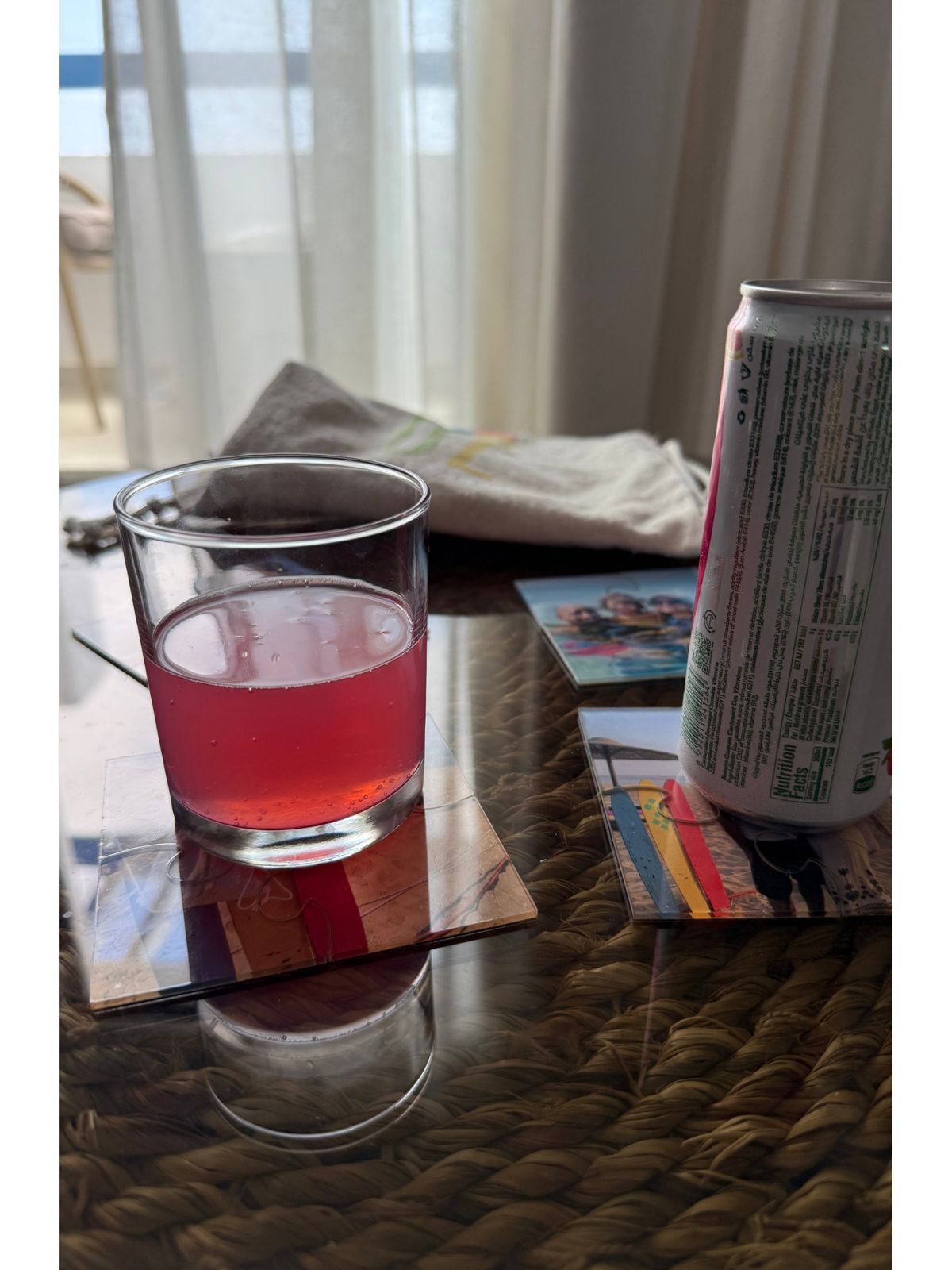 Glass of Tea on a coaster with a can next to it on a table.