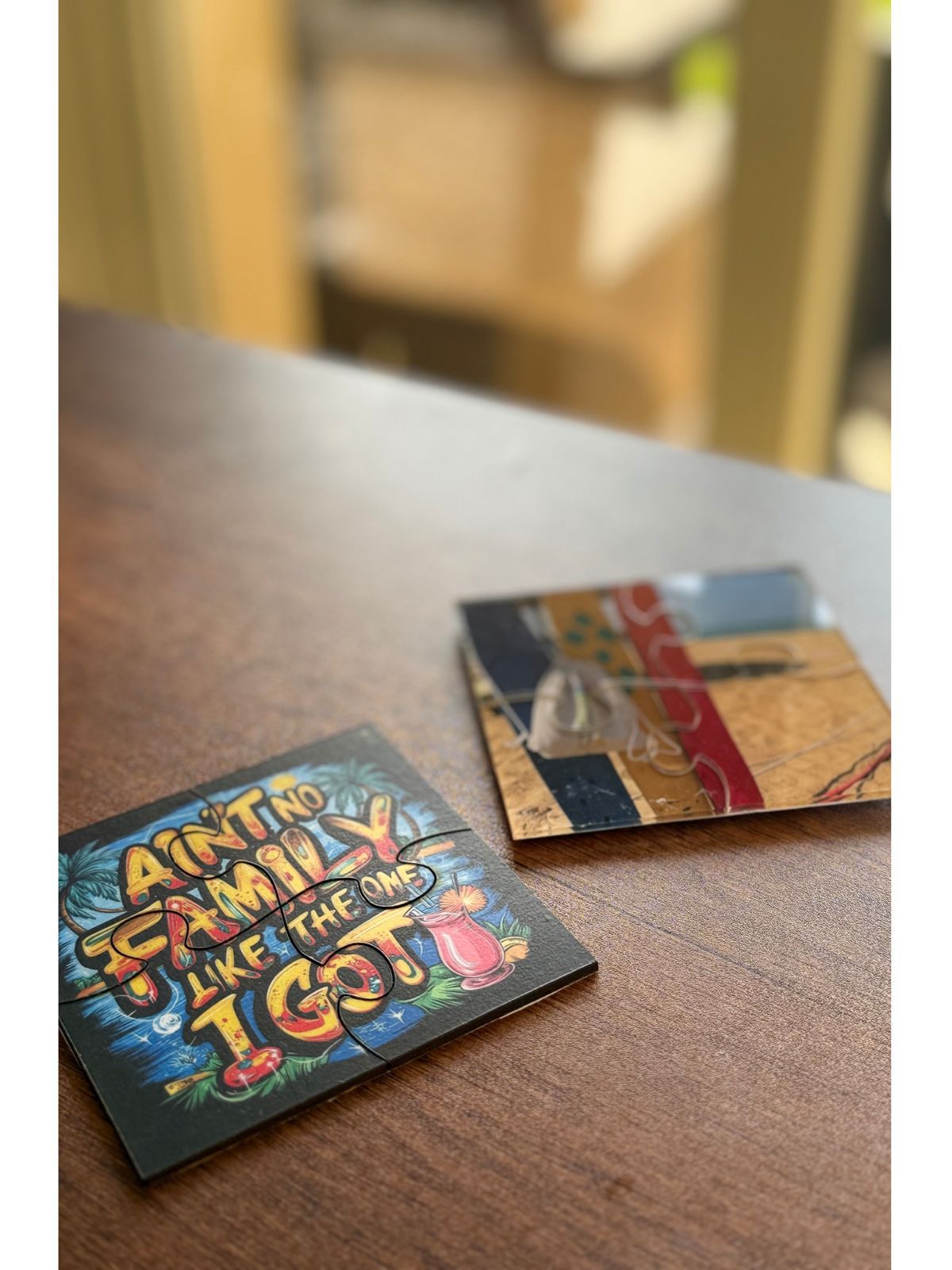 Two decorative coasters on a wooden surface with a blurred background