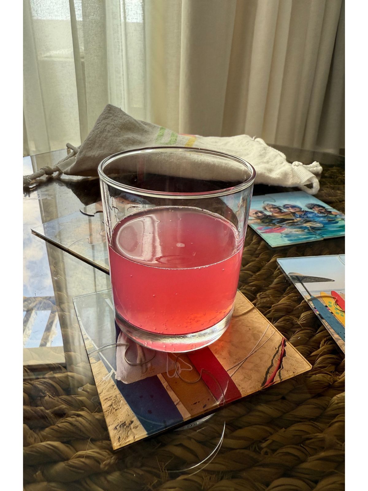 Glass of juice on a coaster with a colorful book in the background